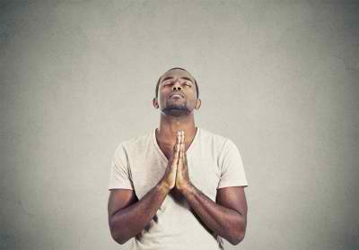 closeup portrait young man praying hands clasped hoping for best asking for forgiveness or miracle isolated gray wall background. Human emotion facial expression feeling