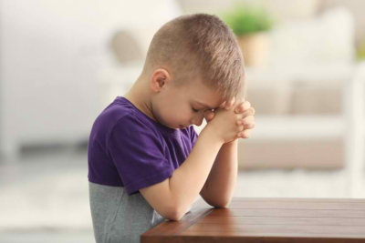Cute little boy praying at home 