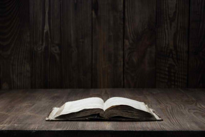 Image of an old Holy Bible on wooden background in a dark space