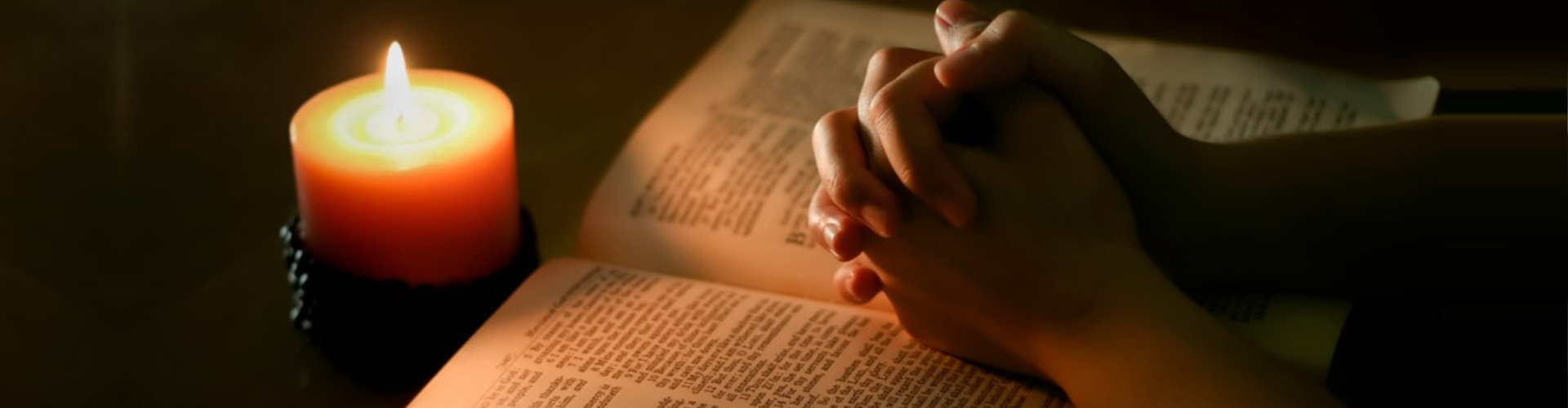 man's hands, bible and candle